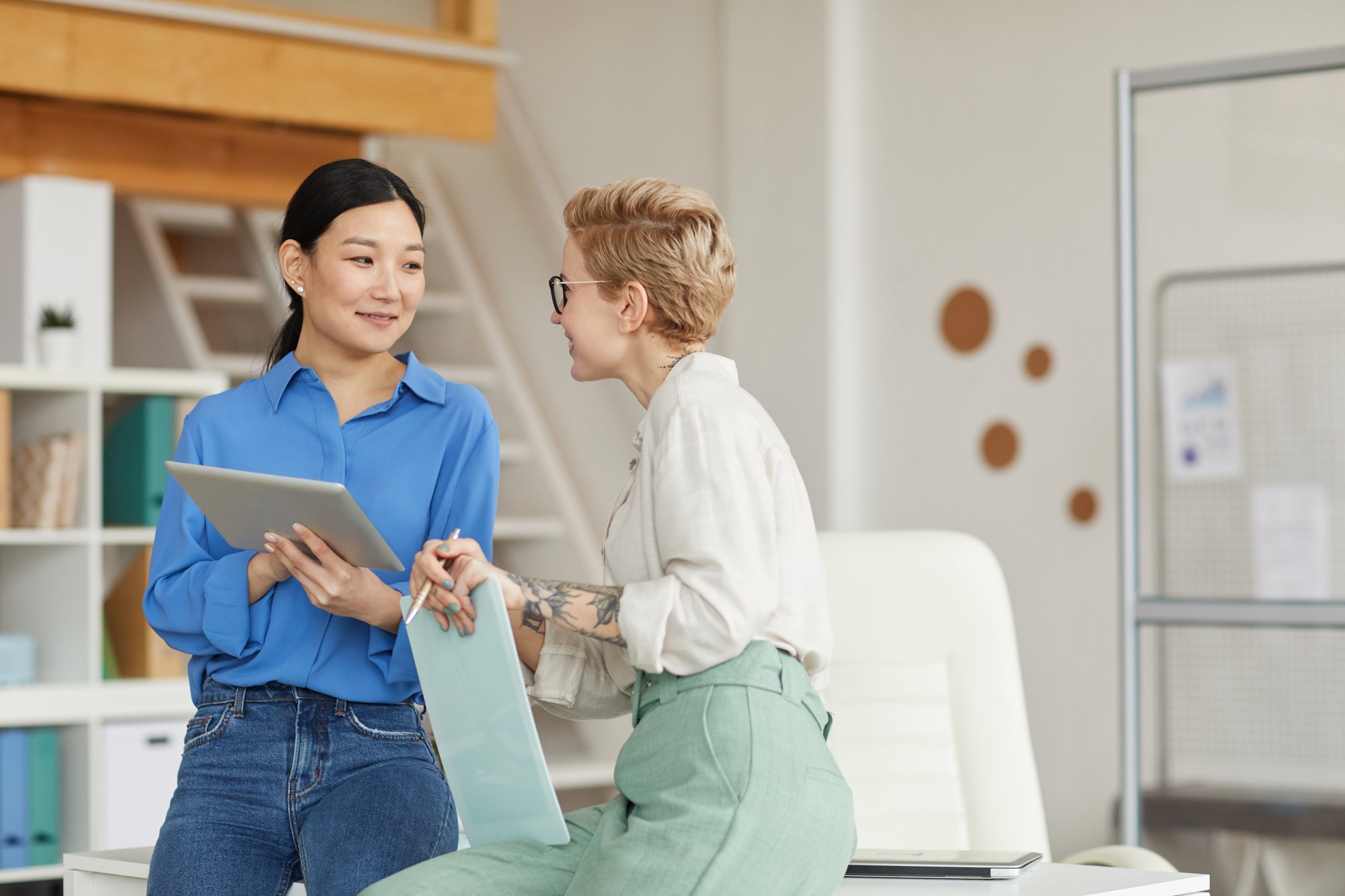 two-smiling-businesswomen-communicating-in-office-2022-02-02-04-50-58-utc